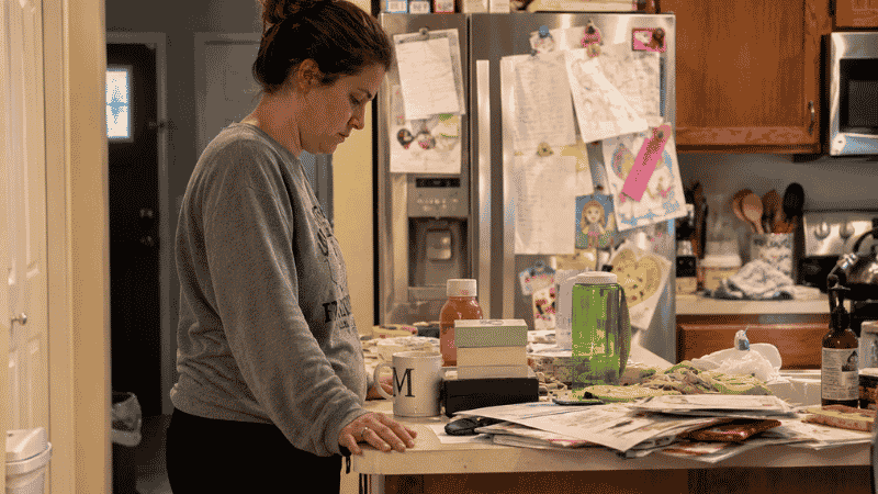 Woman standing in cluttered kitchen looking overwhelmed not knowing where to start decluttering