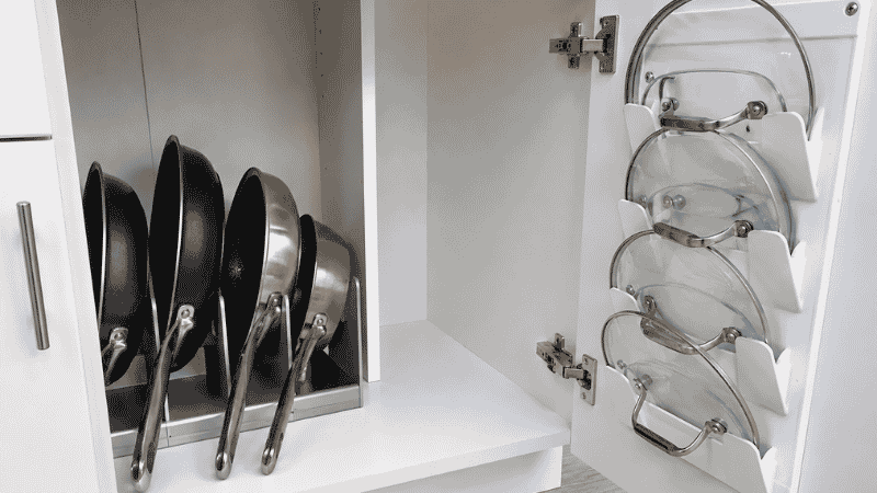 Kitchen cabinet with vertical pan organizer holding skillets upright and door-mounted lid rack keeping lids accessible