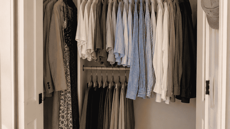Small closet divided into three zones — daily wear center, occasional wear sides, seasonal items on top shelf
