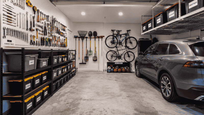 Organized two car garage showing pegboard tool wall garden rack sports zone and overhead storage with clear floor
