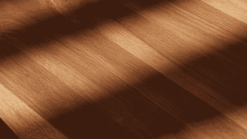 A close-up of the surface of a modern walnut dining table showcases the exquisite matte finish and clear wood grain. The soft shadows of the early morning interweave on the tabletop, highlighting the craftsmanship of high-end furniture.