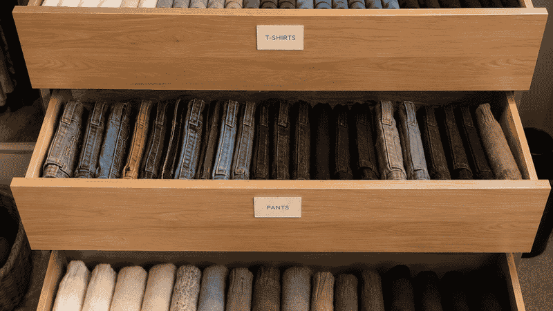 Three dresser drawers showing complete vertical file folding system with shirts pants and sweaters all filed upright and visible