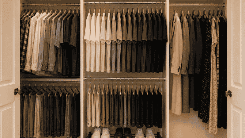 Small closet organized by frequency with daily wear centered double hang rod on left seasonal bins on top and shoe rack on floor